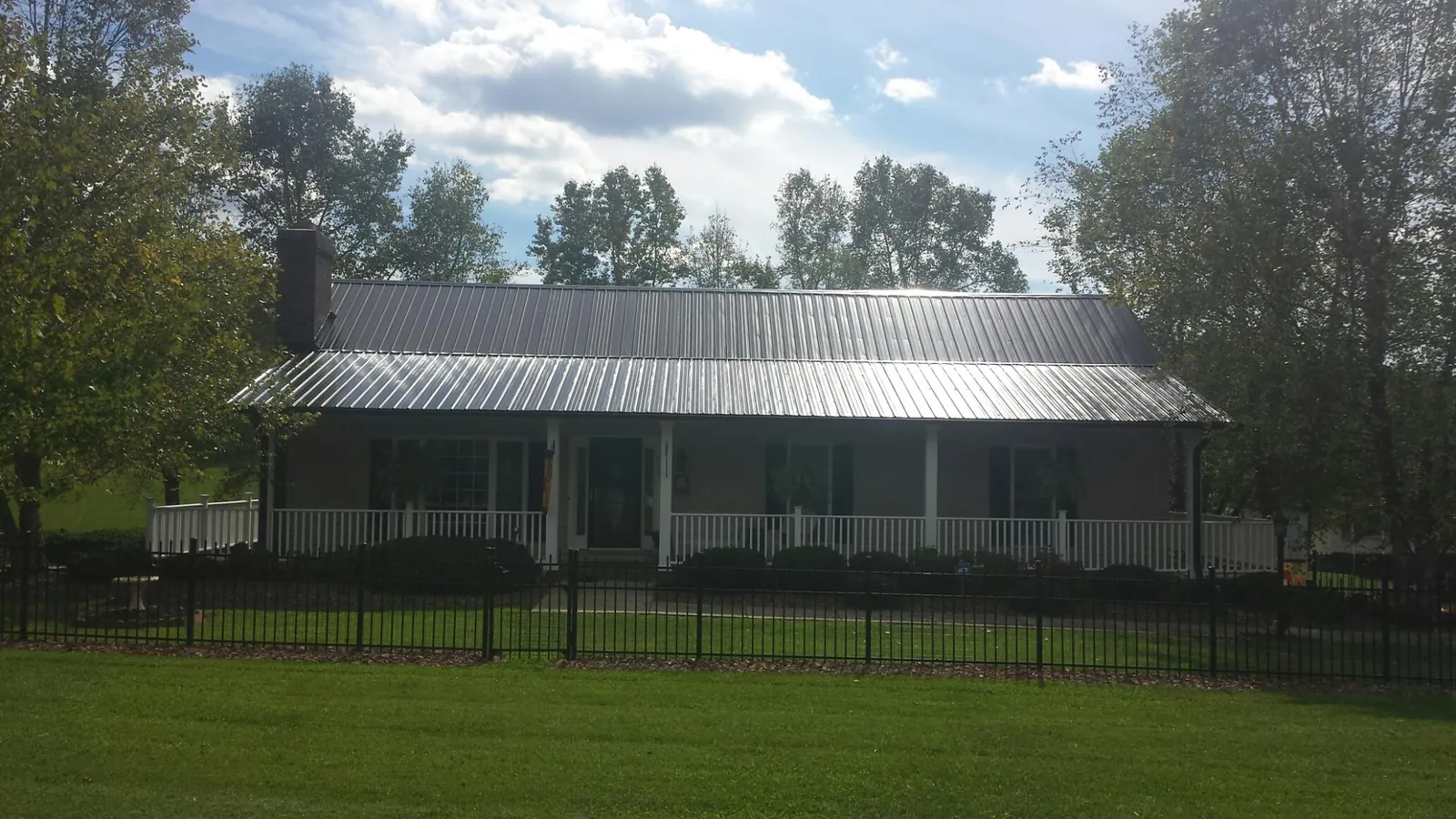 Gray metal roof on a brick ranch with a full width front porch — Gutter Guard Installation work by our crew in Lake City