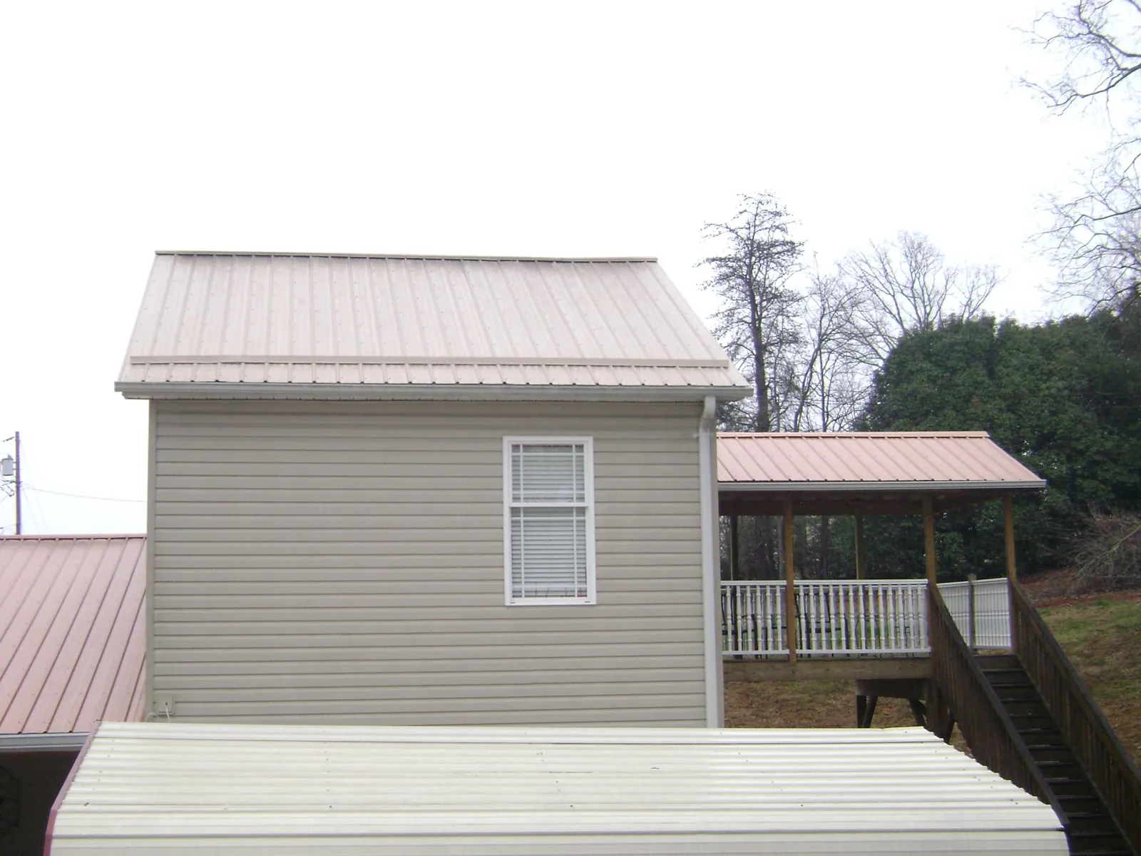 Tan metal roofs on a two story addition and attached porch, from a Roof Replacement job in Lake City
